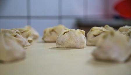 Preparation of manti on a kitchen wooden board. Traditional asian dumplings. Mantu are filled with beef or lamb mixed with minced onions and spices.の写真素材