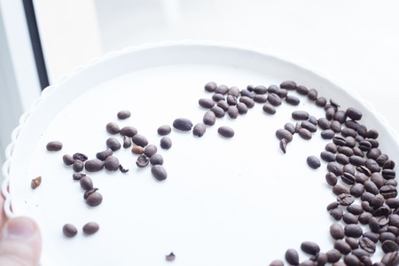 Coffee beans on a white plastic plate. beautifull background. Love. Insparation. On white plate. Romantic.の写真素材