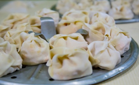 Preparation of manti on a kitchen wooden board. Traditional asian dumplings. Mantu are filled with beef or lamb mixed with minced onions and spices.の写真素材