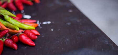 From above pile of red and green pepper placed on dark board background.の写真素材
