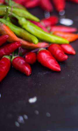 From above pile of red and green pepper placed on dark board background.の写真素材