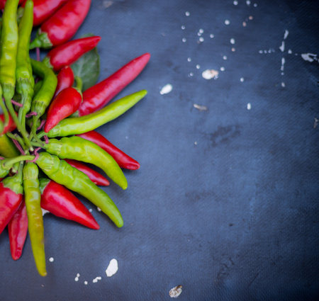 From above pile of red and green pepper placed on dark board background.