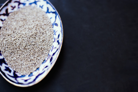 From above shot of ornamental plate filled with fresh aromatic cumin spice.の写真素材