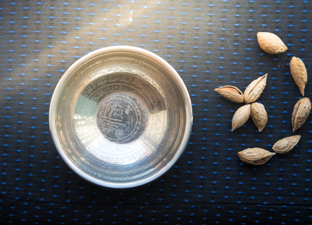 From above metallic dish with Arabic Quran Sura and almonds shaping Islamic moon.の写真素材