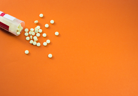 Scattered supplements. Pharmaceutical medicine pills and bottle on orange background. Copy space for text.の写真素材