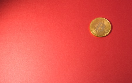 Cryptocurrency physical golden bitcoin coin. Bitcoin, golden bitcoin, yellow bitcoin in red paper backgroundの写真素材