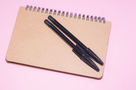 Wooden notepad and two black pens from above on pink background.の写真素材