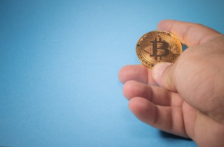 Hand holding golden Bitcoin virtual money. Cryptocurrency physical bitcoin coin.の写真素材