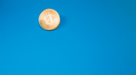 Cryptocurrency physical golden bitcoin coin. Bitcoin, golden bitcoin, yellow bitcoin in blue paper backgroundの写真素材