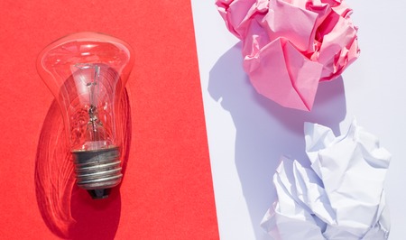 A bulb and crumpled papers on divided background from aboveの写真素材