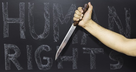Human rights concept: Man holding knife against the text: Human rights day written with chalk on blackboard.の写真素材