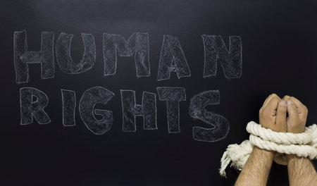 Human rights concept: chained man against the text: Human rights day written with chalk on blackboard.の写真素材