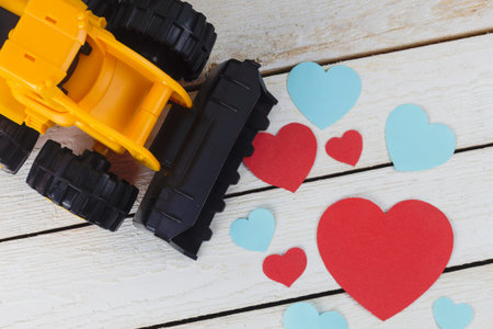 Bulldozer starting to keep the fallen hearts on white wood backgroundの写真素材