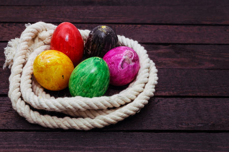 Painted Easter egg in rope on wood background.の写真素材