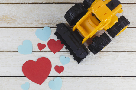 toy bulldozer collects paper heartson white wood tableの写真素材
