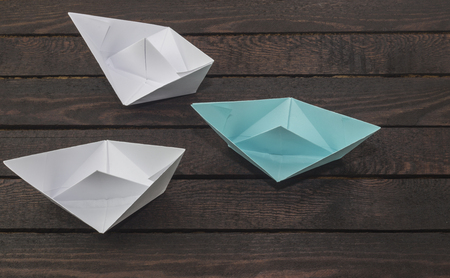 Leadership concept, blue leader boat leading whites, on dark wooden background.の写真素材