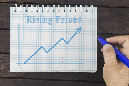 business, finance, investment, saving and cash concept - business man drawing graph of rising prices on notepadの写真素材