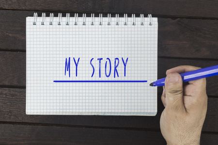 Human hand writing with marker on notepad: My storyの写真素材