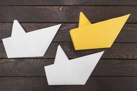 Three paper boats on dark wooden background.の写真素材