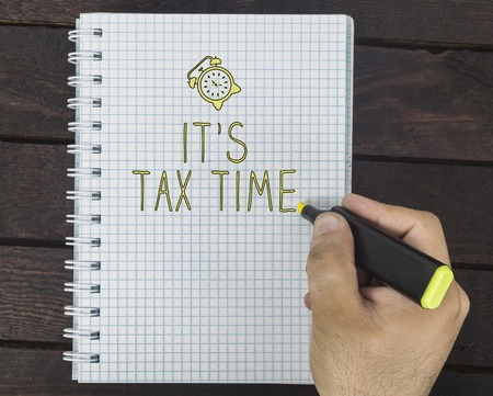 hand writing It's tax time on notepad on the dark wooden deskの写真素材