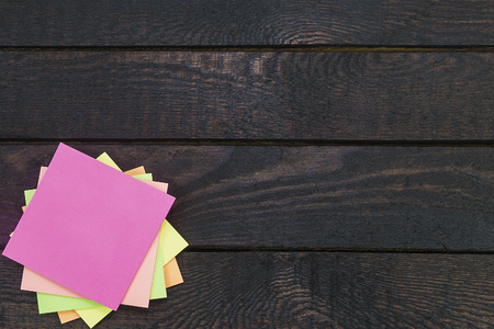 Stack of color stickers on dark wooden table.の写真素材