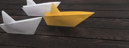 Three paper boats on dark wooden background.の写真素材