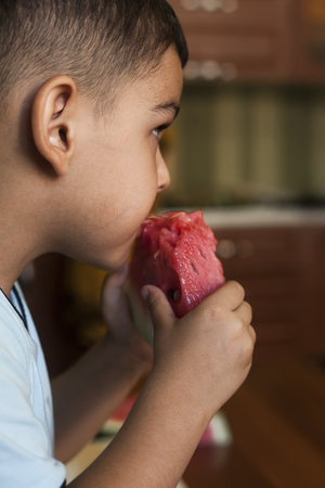 Cute little boy eating Watermelon and watching tvの写真素材