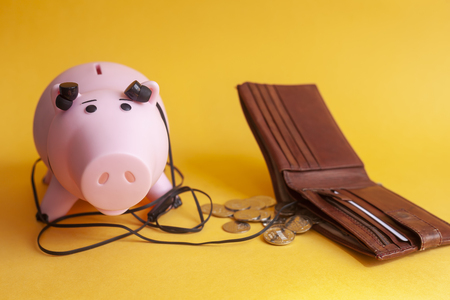 concept of listening to the money market, piggy bank with earphones listen a wallet on yellowの写真素材