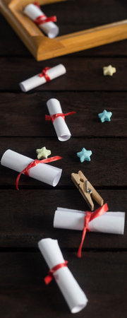 Flat lay romantic background. Top view to giftbox, rolled wish papers, and wooden frame with paper...