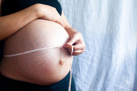 Pregnant woman with measuring tape, measures her belly circumferenceの写真素材