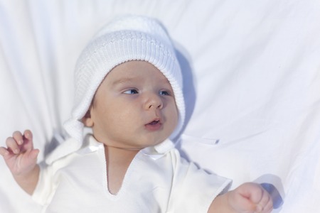 Adorable newborn baby boy lying on belly in white sunny bedroom or nurseryの写真素材