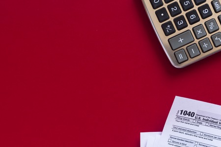 US tax form 1040 with calculator on red background. Copy space.の写真素材