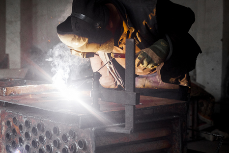 Man welds metal. Worker welding steel in industry with safety mask safety gloves and safety equipment. Metal industry welding concept.の写真素材