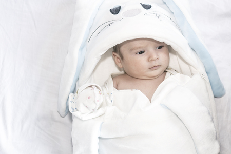 Adorable cute newborn baby boy on white background. The lovely child wore on rabbit costume with long ears. Holiday, Easter, childhood concept.の写真素材