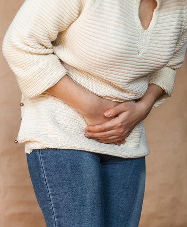 Young woman having a painful stomachache. Chronic gastritis. Abdomen bloating and healthcare...