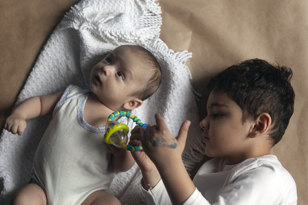 Two brothers lying and posing. Portrait of brothers. Two months baby boy and five years small boy playing cheerfully. View from above. Flat lay photo. Emotional expressions of children.の写真素材