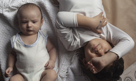 Two brothers lying and posing. Portrait of brothers. Two months baby boy and five years small boy playing cheerfully. View from above. Flat lay photo. Emotional expressions of children.の写真素材