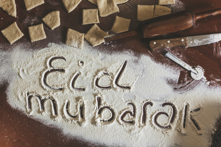 Eid Mubarak phrase written on flour. Preparation process of traditional arabic muslim cooksの写真素材