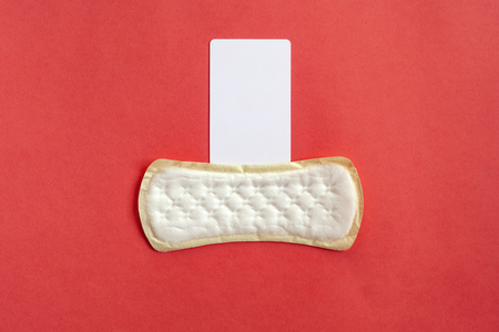 Feminine hygiene pad with blank white paper on red background.の写真素材