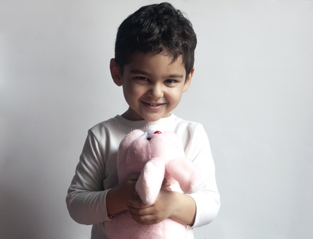 Portrait of 4-5 years adorable old boy playing with soft plush cute rabbit bunny toyの写真素材