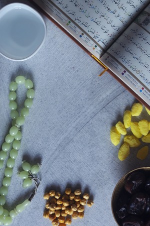 Holy Quran, Rosary, Iftar sweets and dried fruits with a cup of water. View from above. Flat lay photo. Empty spaceの写真素材