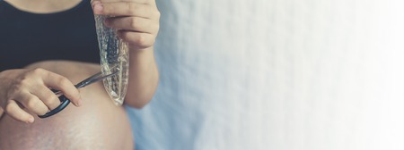 Pregnant woman cutting a condom with scissorsの写真素材