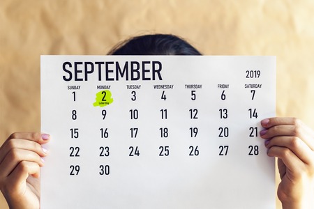 A woman holding August calendar with marked Labor Day. 2nd September marked with a marker at 2019 calendar.の写真素材
