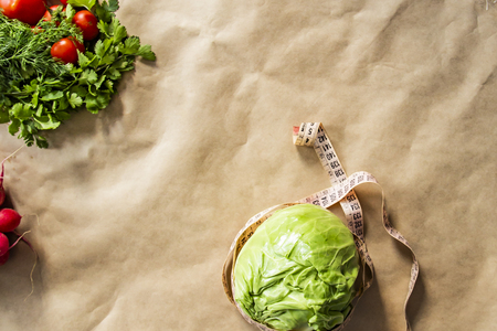 Fresh green cabbage vegetable with measure tape on brown paper background.の写真素材
