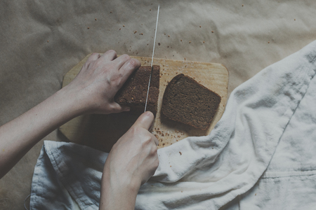 Housewife cutting a bread. Female cut bread on cutting board. View from above. Top view of breads.の写真素材