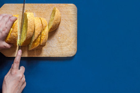 Food concept. Hand cutting bread. Slicing a bread. Top view. Copy space