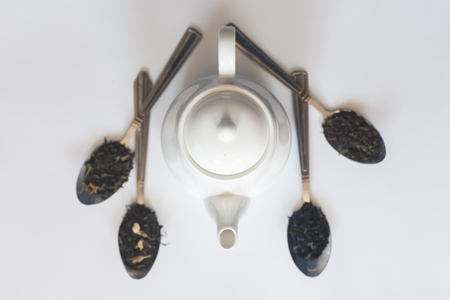 White ceramic tea pot and various dried teas on the white background. Flat lay view. Copy spaceの写真素材