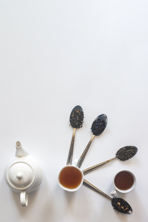 Tea set with white ceramic tea pot and other tea ingredients on the white. Flat lay view of various dried teas and teapot. View from above. Copy spaceの写真素材