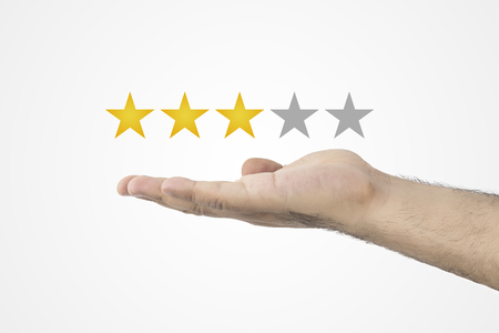 3 Star Rating. Hand holding three star rating of five. Customer review concept. ating golden stars. Feedback, reputation and quality conceptの写真素材
