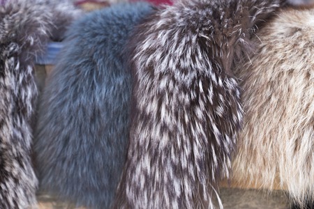 fur scarf store. Selling women's natural fur scarf at outdoors. Trading with fur shawlsの写真素材